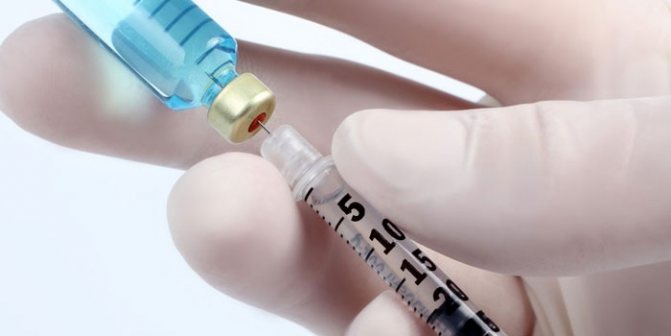 Медик наполняет шприц вакциной